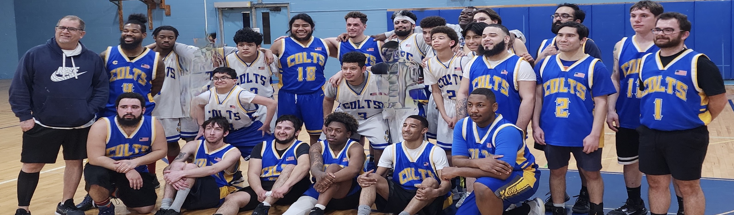 Group picture of MKSD men's alumni game participants. Students are wearing white uniforms and alumni are wearing blue uniforms.